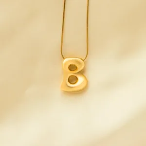 Gold puffy letter pendant necklace, minimalist snake chain detail shot for modern fashion style.