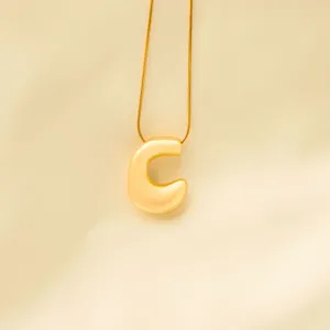 Close-up of a stylish gold puffy letter C pendant with delicate chain, elegant detail view.