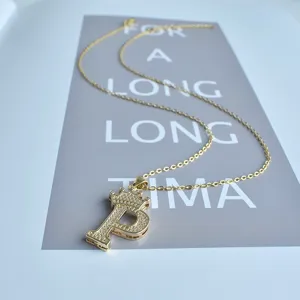 Détail de collier pendentif lettre P couronne dorée, chaîne clavicule en strass brillants