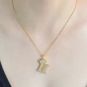 Vue détaillée d'un collier lettre H couronne dorée avec des strass brillants scintillants.