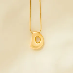 Gold initial bubble letter pendant necklace detail, elegant close-up view of the chic chain.