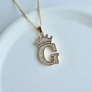 Détail en gros plan du collier pendentif lettre G couronne dorée avec oxydes de zirconium.