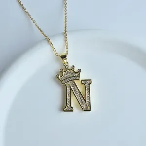 Collier pendentif lettre N couronne dorée avec des strass scintillants, vue de détail.