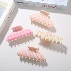 Lot de quatre pinces à cheveux à carreaux et à rayures dans des tons rose pastel et crème.