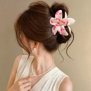 Primer plano de pinza de pelo de plumeria rosa con estampado de cerezas en moño.
