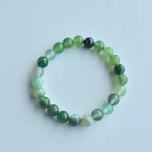 Detailed close-up of green natural stone beaded bracelet showing smooth texture and elastic cord.