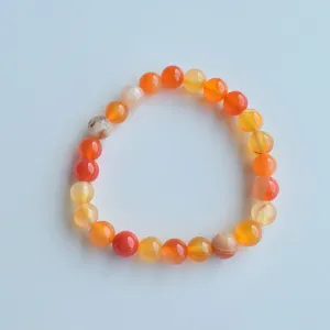 Red agate beaded bracelet detail, natural gemstone stretch crystal jewelry piece.