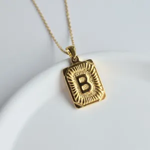 Close-up detail of the gold stainless steel square letter B pendant necklace on white dish.