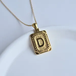 Close up detail of gold stainless steel initial letter D pendant necklace fashion accessory.
