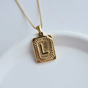 Close up detail view of a stylish gold stainless steel letter L square pendant necklace.