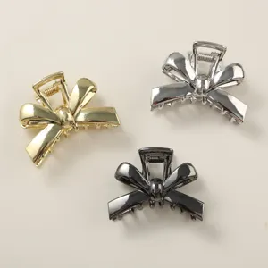 Detail of three metallic bow hair claw clips in gold, silver, and gunmetal black.