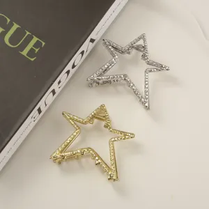 Close-up of gold and silver star-shaped metal hair clips with textured finish
