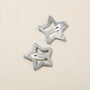 Primo piano di due fermagli per capelli a forma di stella glitterata argento su sfondo beige