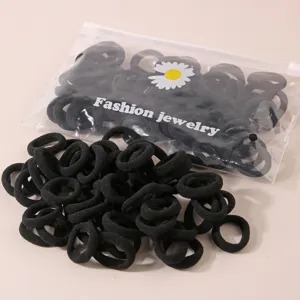 Nahaufnahme von schwarzen Haargummis im Set mit Gänseblümchen-Verpackungsbeutel.