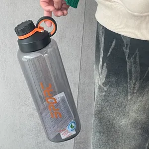 Grande bouteille d'eau de sport gris translucide tenue à la main dans un cadre de vie réel.