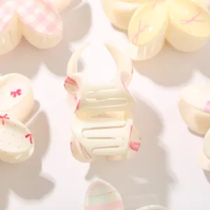Primer plano detallado de una pinza de pelo crema con lazos rosas y bonitos estampados florales.
