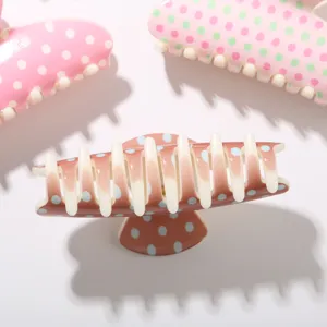 Gros plan sur des pinces à cheveux de 10,5 cm avec motifs à pois colorés sur fond blanc.