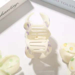 Primer plano de pinza para el cabello de ABS crema con dulce estampado floral lila