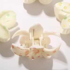 Detalle de una pinza para el pelo de ABS crema con estampado floral y resorte de metal dorado
