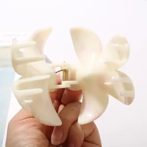 Primer plano de una pinza para el pelo de flor de frangipani en ABS blanco con detalles rosa