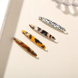 Detailed view of set of 4 tortoiseshell and marble acetate hair barrettes on desk.