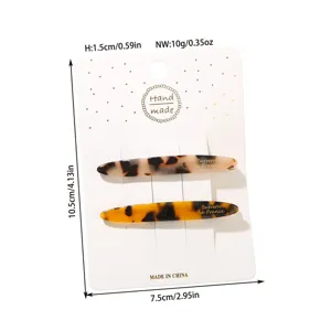 Detailed view of two tortoiseshell acetate hair clips on a measurement display card.
