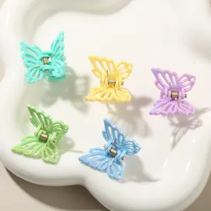 Dettaglio macro di mini mollette a farfalla olografiche in colori pastello su vassoio