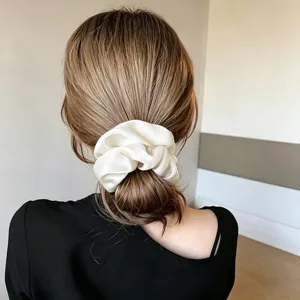 Detail view of large silk-like scrunchie in ivory for elegant bun hair styling.