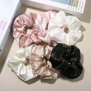 Macro view of five assorted satin scrunchies showing elegant texture and smooth silk-like shine