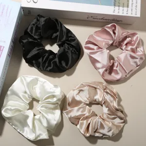 Detailed macro shot of four oversized satin hair scrunchies in neutral and pastel colors