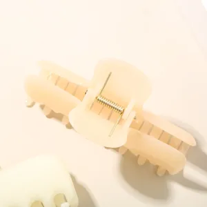 Dettaglio della molla in metallo dorato su una pinza per capelli beige effetto gel