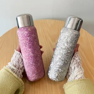 Vista detallada de dos botellas térmicas de titanio moteado sobre una mesa de madera