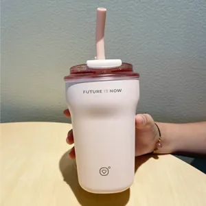 Close-up of pink insulated coffee tumbler with Future Is Now text held by person