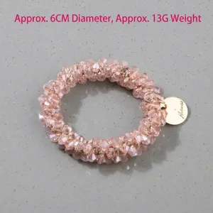 Macro view of elegant handmade pink crystal beaded hair tie with a gold metal tag