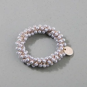 Detailed macro shot of a hand-woven hair tie decorated with elegant grey faux pearls