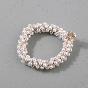 Close-up detail of a handmade white pearl hair scrunchie with a gold metal charm