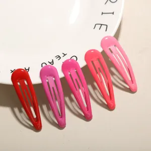 Nahaufnahme von fünf farbenfrohen rosa und roten Wasserentropfen-Haarclips auf einem Teller
