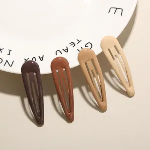 Detailansicht von vier erdfarbenen Haarclips, die an einem weißen Teller lehnen.