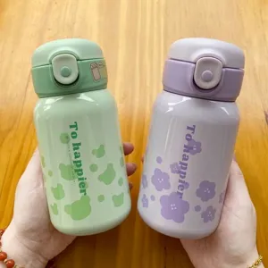 Dos botellas térmicas de acero inoxidable 316 con diseños de osos y flores en la mano