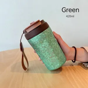 Nahaufnahme einer grün texturierten Kaffeetasse aus reinem Titan mit Trageriemen
