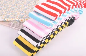 Close-up detail of colorful striped and checked over-the-knee socks, soft knit fabric for daily wear.