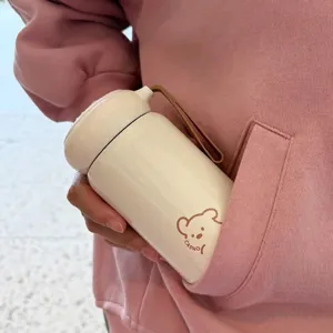 Nahaufnahme einer cremeweißen Mini-Isolierflasche mit süßem Bärenmuster-Design