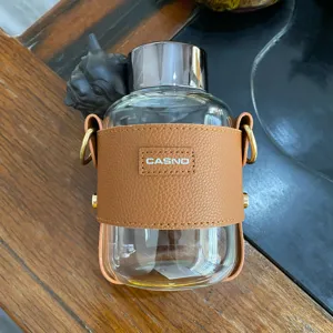 Nahaufnahme der braunen Ledermanschette mit CASNO-Logo auf einer Glaswasserflasche