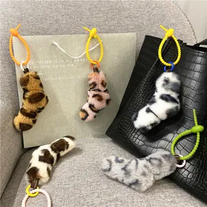 Detailed macro view showing plush leopard and cow print twist charms on a black bag