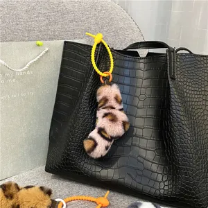 Fashionable leopard print plush keychain pendant on a black crocodile leather tote bag
