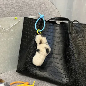 Leopard print fuzzy plush bag charm with blue twist knot strap on a black leather tote