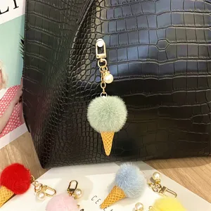 Mint green plush ice cream keychain with pearl charm detail shown on a black leather bag.