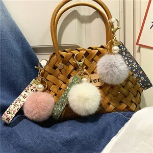 Detailed view of floral ribbon keychains with soft plush pom-poms and pearl accents