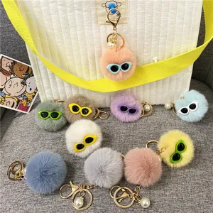 Close-up detail of colorful plush monster keychains featuring sunglasses and pearl charms.