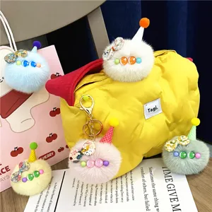 Detail of multiple colorful plush pompom ice cream keychains with cute hats and bows